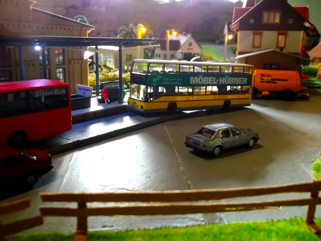 Dieser MAN SD 202 D89 (Hersteller Wiking) im Farbkleid der BVG mit Mbel Hbner-Reklame fhrt gerade den Bahnhof meiner Modelleisenbahnanlage an.
Im Vordergrund befindet sich ein Mercedes-Benz W201 190E.