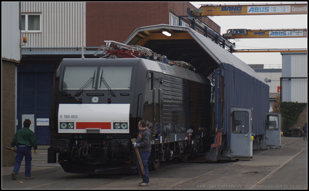 Mit schwarzen Neulack verlsst MRCE E 189 803 die Schiebebhne um auerhalb des Stadler-Gelndes zwischengeparkt zu werden (NVR-Nummer 91 80 6189 803-0 D-DISPO, gesehen Berlin-Reinickendorf 01.12.2011)