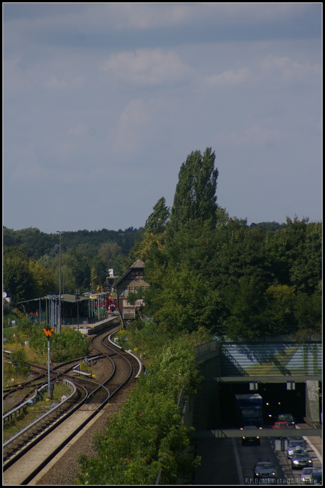 Whrend der Autoverkehr auf der A111 fliet, geht es auch bei der S-Bahn voran. Inzwischen ist auch der Betrieb zwischen Tegel und Teltow Stadt wieder aufgenommen und an Gleisen sowie der Stromschiene wird krftig gearbeitet. Blick auf den S-Bahnhof Tegel, das alte Stellwerk Tgl, die zum Waidmannsluster Damm geschleppten Wagen und Zweiwegebagger an der Baustelle (Berlin Tegel 23.08.2012)