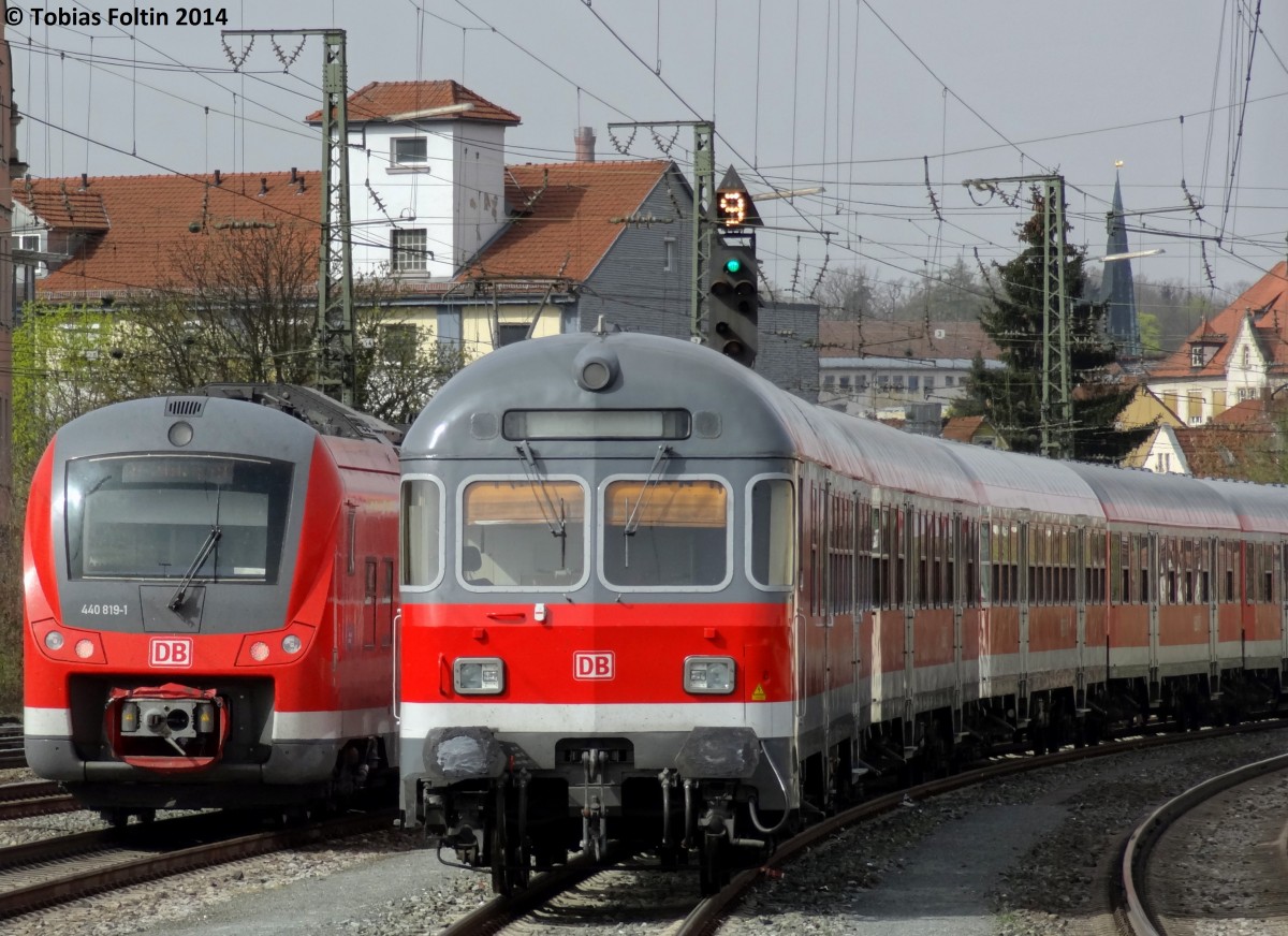 Ein Wendezug mit n-Wagen steht in Ansbach abgestellt um im Berufsverkehr eine Verst�rkerleistung nach Crailsheim zu �bernehmen. Links huscht ein 440er nach W�rzburg Hbf an der Garnitur vorbei.
Aufgenommen im April 2014.