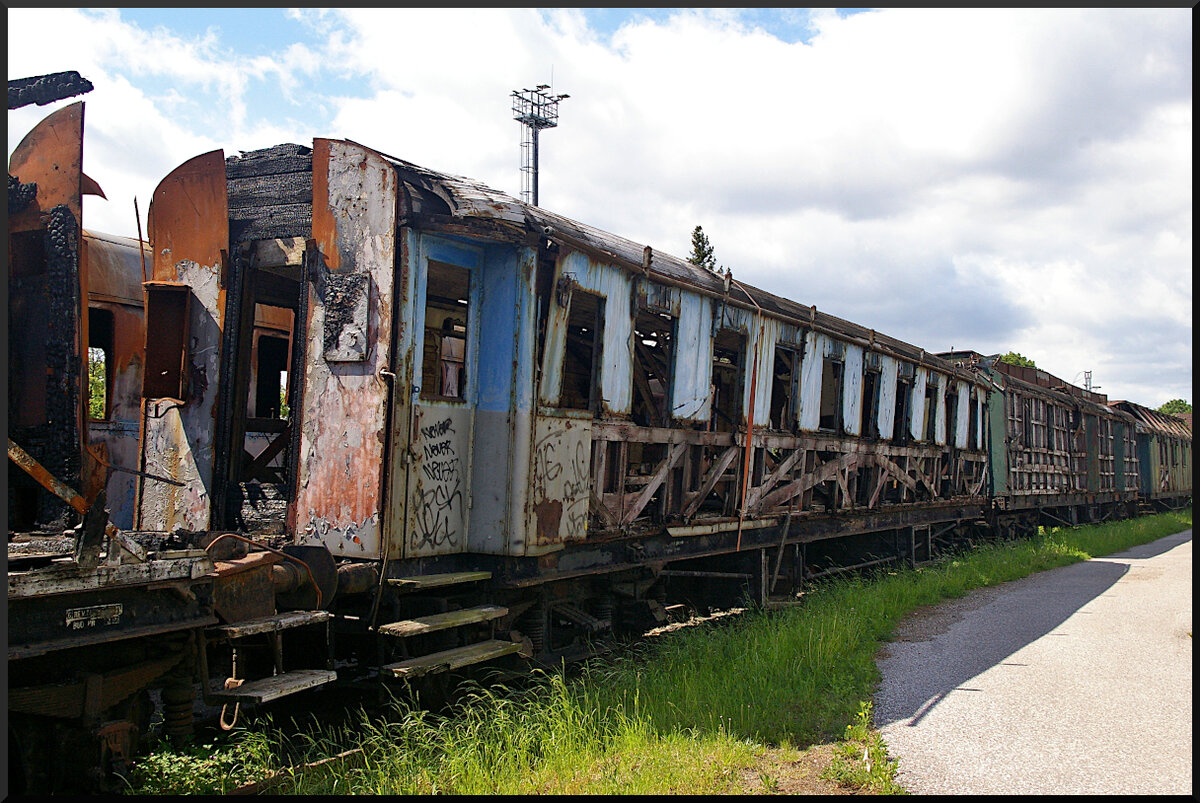 Im innern dieses Schnellzugwagen(?) wurde auch Feuer gelegt und hat ihn stark beschädigt, so das er nur noch mit einem Spanngurt zusammengehalten werden kann. Eine ČSD-Nummer war auch am Rahmen nicht mehr erkennbar. Der Wagen steht auf einem Abstellgleis im Eisenbahnmuseum Jaroměř.

Jaroměř, 21.05.2022
