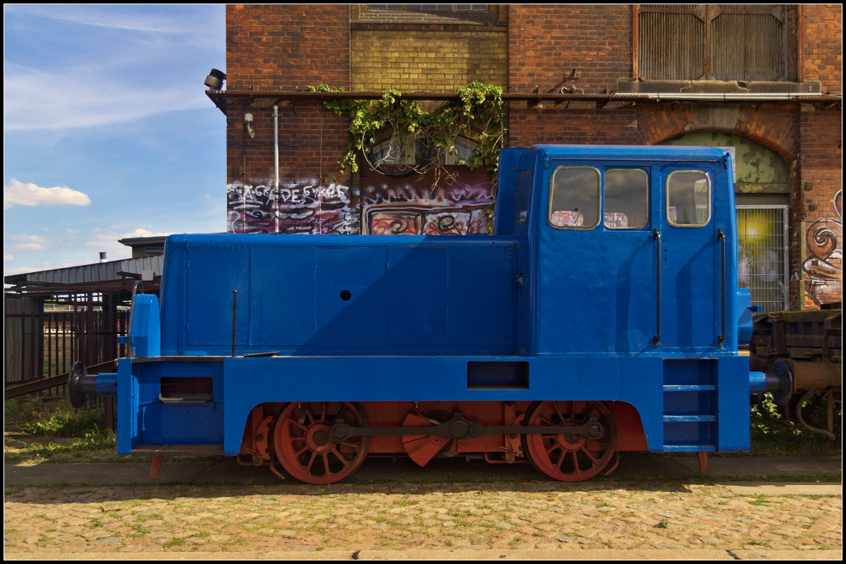 Mit Neulack versehen stand am 08.09.2018 die MHG 21 der Magdeburger Hafen GmbH auf den Gleisen am Wissenschaftshafen. Während des Familienfest der Magdeburger Eisenbahnfreunde e.V. konnte die Lok am 08.09.2018 entdeckt werde. Gebaut wurde die V 22 im Jahr 1967 bei LKM mit der Nummer 262005 und wurde im gleichen Jahr an VEB Gießereianlagen Leipzig ausgeliefert. 1969 kam sie nach Magdeburg-Rothensee zum VEB Magdeburger Armaturenwerke  Karl Marx . Bei der Stahlgießerei in Rothensee blieb sie bis zur Stillegung. Als MHG 21 übernahm sie dann die Magdeburger Hafenbahn. Da sie nur auf den Gleisen des Firmengeländes unterwegs war, hat sie nie eine Registrierung erhalten.