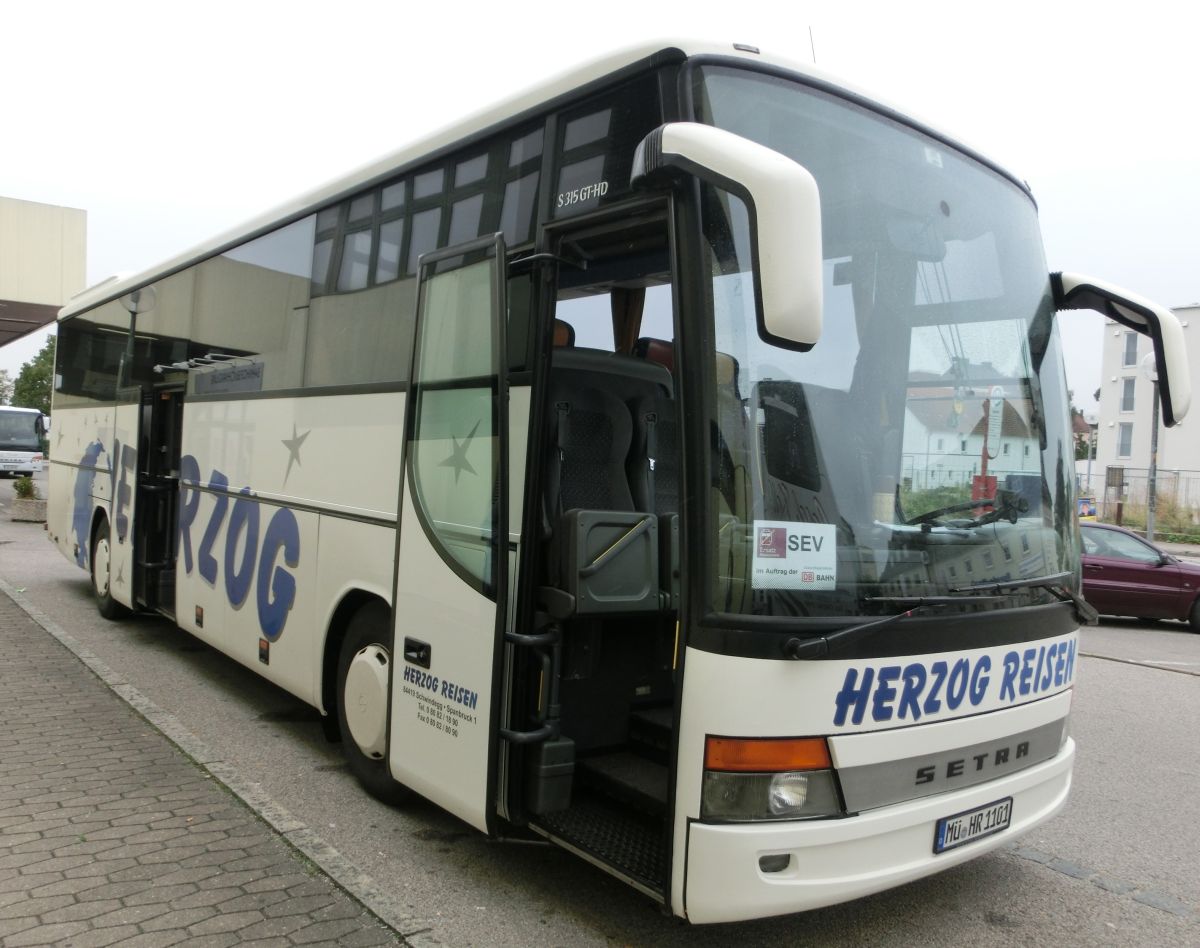 Setra S 315 GT-HD von Herzog Reisen aus Spanbruck bei Schwindegg. Da es sich um die Faceliftvariante handelt, ist er aus dem Bauzeitraum 2002-2004. Als Reisebus ist er selbstverständlich mit TV-Anlage, Bordküche und Toilette sowie mit 48+2 Setra-Schlafsesseln vom Modell 'Top' ausgestattet. Angetrieben wird er von dem stehend eingebauten Reihensechszylinder MB OM 457 LA und von dem MB-Sechsgang-Schaltgetriebe GO 190-6.
Ablichten konnte ich ihn am 28. 8. 2013 vor dem Mühldorfer Bahnhof, als er auf einem Schienenersatzverkehr zwischen Mühldorf und Dorfen (Bahnstrecke Mühldorf - München) eingesetzt wurde.