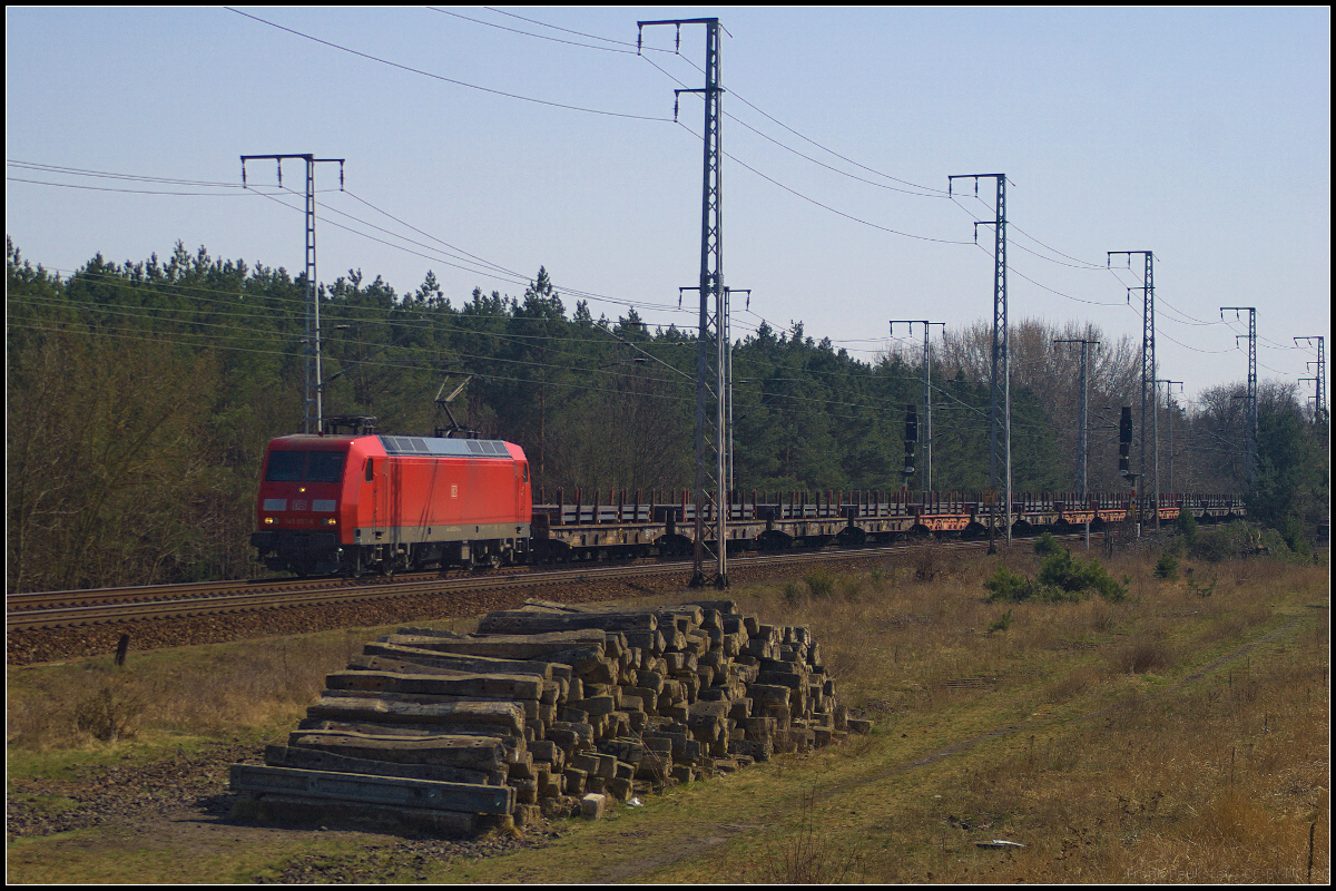 Unerwartet kam DB Cargo 145 057-6 mit ihrem Stahlplattenzug durch die Berliner Wuhlheide gefahren. So blieb nur ein Notbild am 09.04.2018 quer über zwei Fotostandorte hinweg um sie noch zwischen den hohen Oberleitungsmasten zu erwischen.