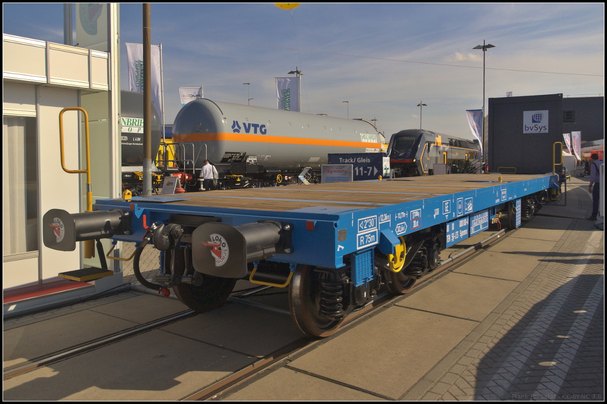 Vierachsiger Drehgestell-Flachwagen in Sonderbauart der Gattung Sgmmns mit Holzbohlen als Boden. Ausgestellt war der Flachwagen ohne UIC-Nummer während der InnoTrans 2018 auf dem Freigelände.