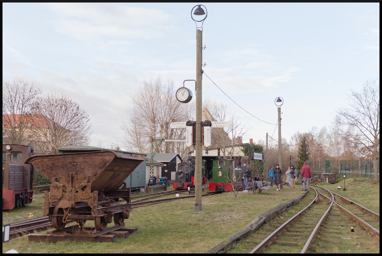 Blick auf den Museumsbahnhof der Museumsfeldbahn Leipzig-Lindenau. Von hier fahren die Personenzüge nach Leipzig Lachen und Schomburgkstraße. Bei anderen Anlässen werden auch andere Ziele angefahren. Der Fahrtzielanzeiger ist mechanisch und in Schönschrift beschriftet. Vorne ist eine typische Kipplore wie sie auf der Feldbahn eingesetzt wurde. Beim Fahrtag  Glühweinfahrten 2023  konnte man auch ausgiebig die ausgestellten Fahrzeuge begutachten (Leipzig-Lindenau, 29.12.2023)